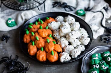 A plate of Halloween walnuts decorated to look like pumpkins and mummies.
