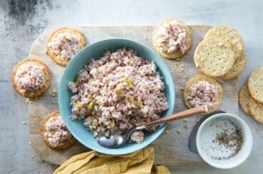 Ham salad in a teal bowl surrounded by crackers.