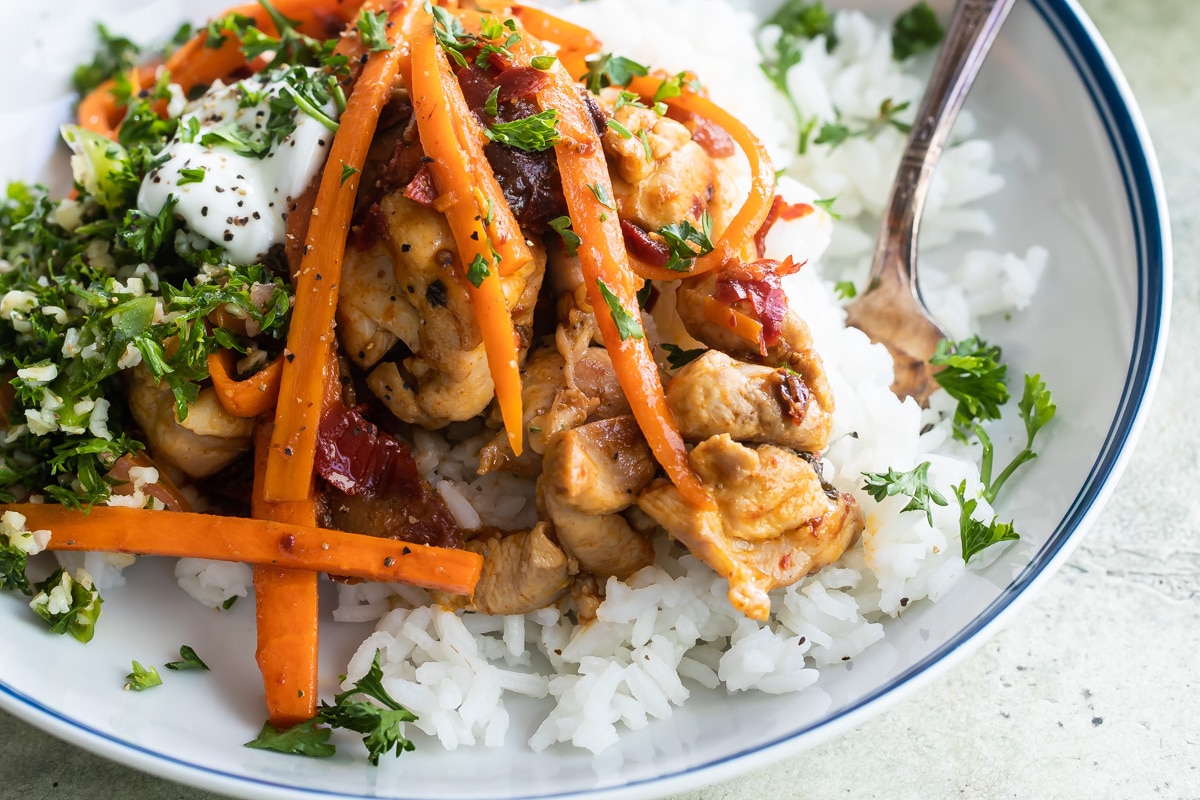 A white plate with Harissa chicken and rice.