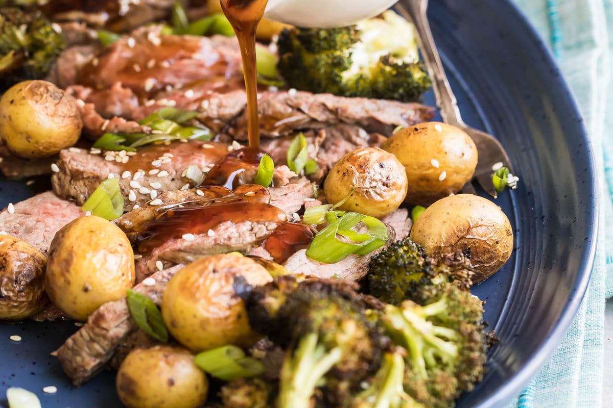 A platter of Hibachi Steak with Grilled Wasabi potatoes and teriyaki sauce being drizzled over it.