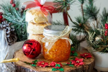 A jar of orange marmalade with a stack of biscuits, both wrapped as Christmas gift.