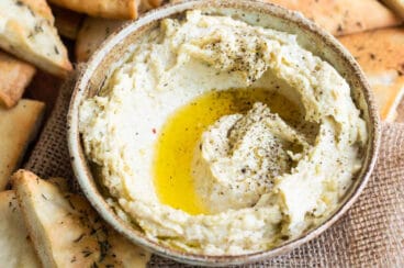 Homemade hummus with zaatar butter in a bowl with pita chips.