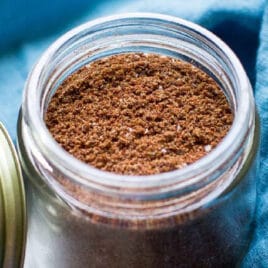 Taco seasoning in a glass jar with a blue napkin around it.