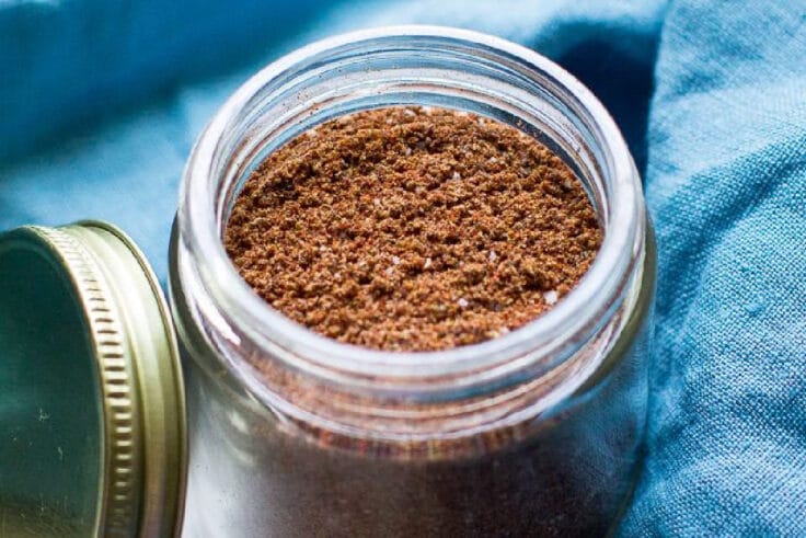 Taco seasoning in a glass jar with a blue napkin around it.
