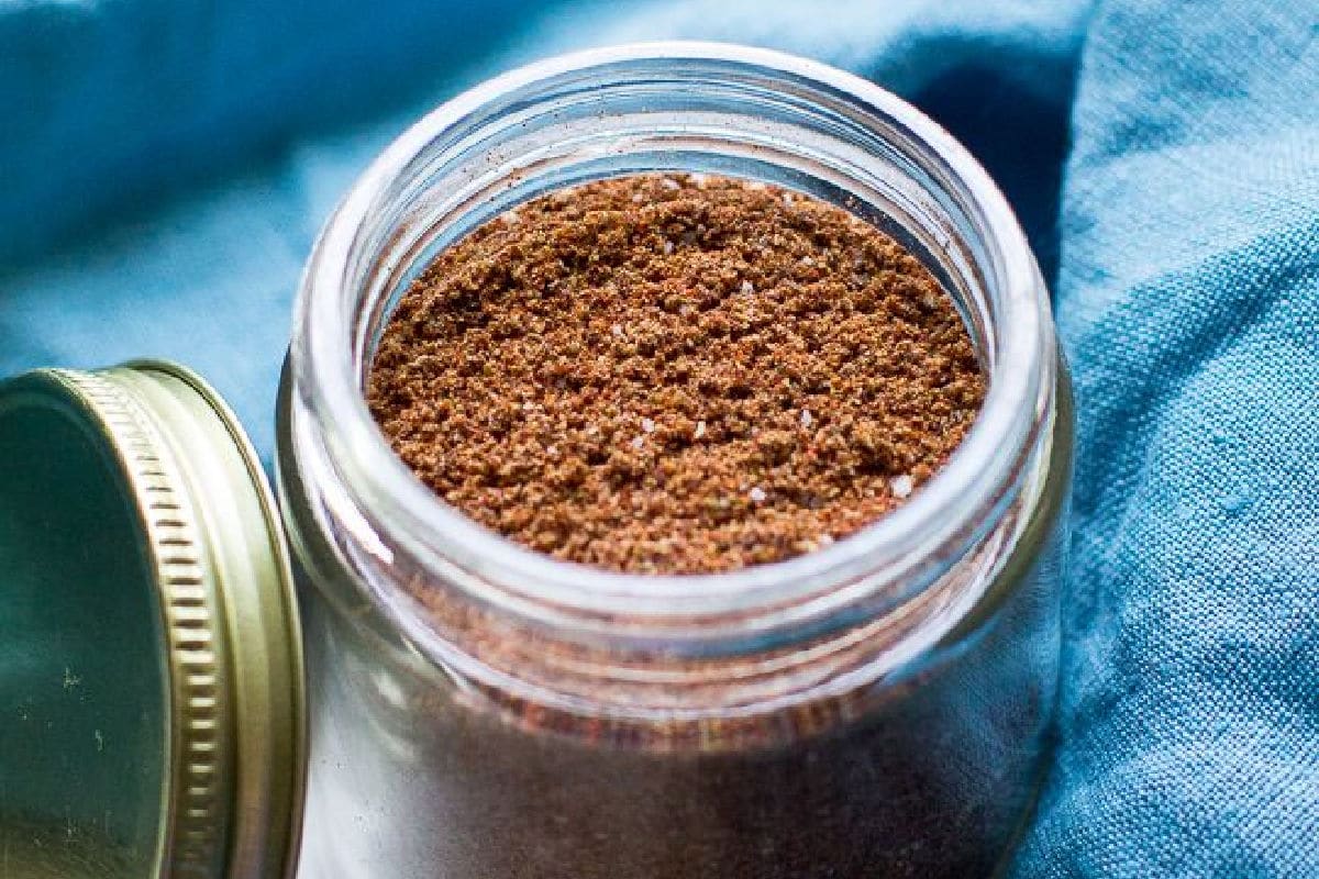 Taco seasoning in a glass jar with a blue napkin around it.