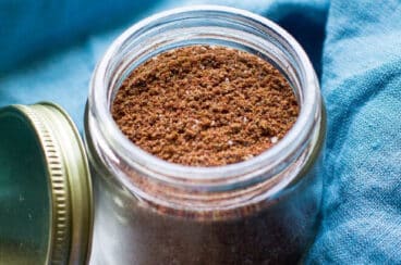 Taco seasoning in a glass jar with a blue napkin around it.