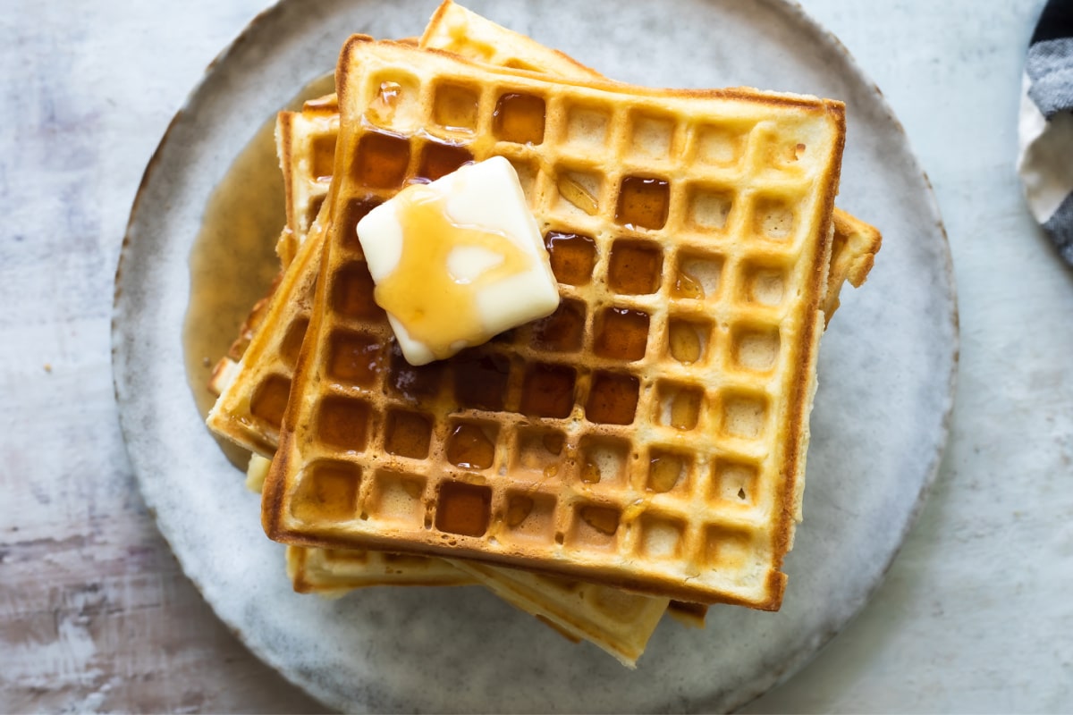 A stack of homemade waffles with syrup.