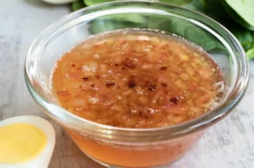 Hot bacon dressing in a clear bowl on a countertop.
