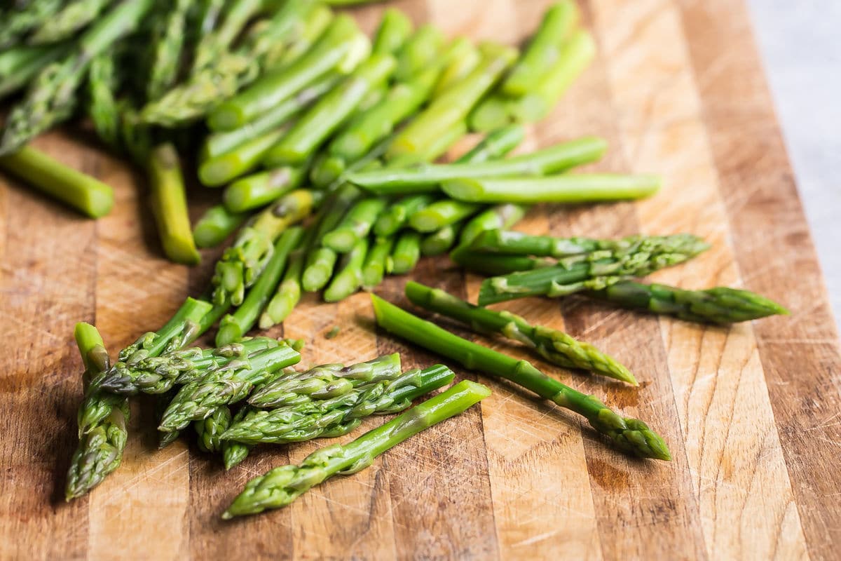 Chopped asparagus on a wood cutting board.