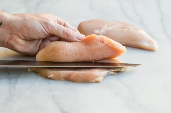 Somebody butterflying a chicken breast.
