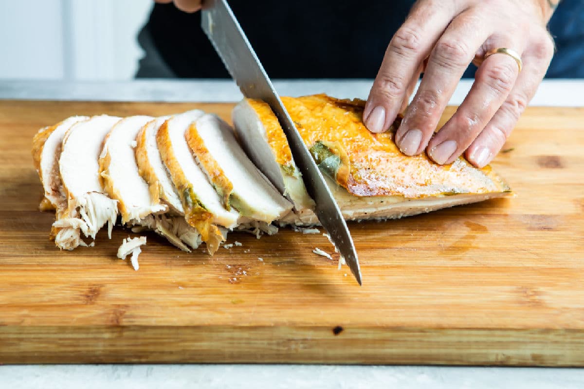 Carving roasted turkey breast into slices.