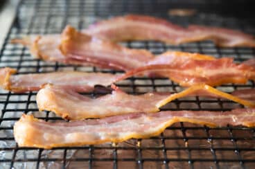 Cooked bacon on a rack set over a foil-lined baking sheet.