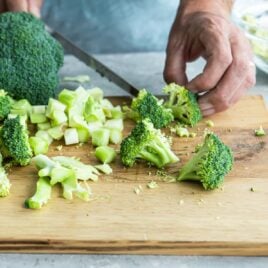 Cut up broccoli on a cutting board.