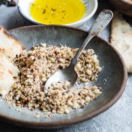 Dukkah on a blue plate with pita bread.