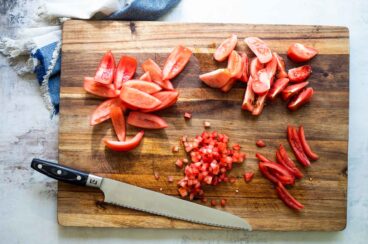 Seeding tomatoes on a cutting board.