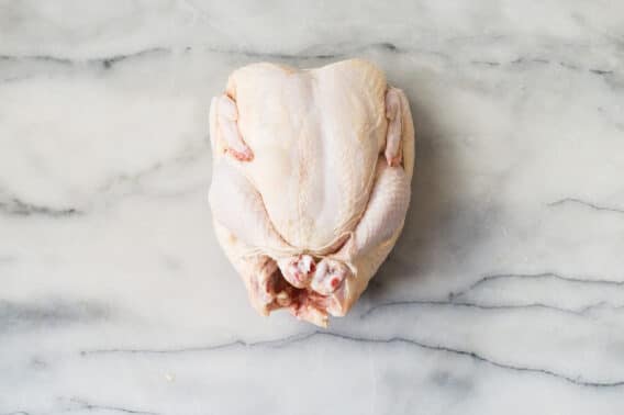 Someone trussing a raw chicken.