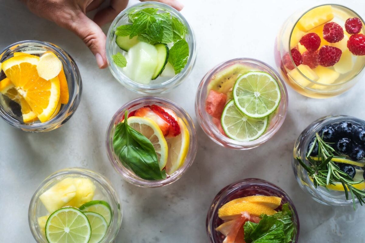 Glasses of water infused with fruit, vegetables, and fresh herbs.