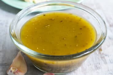 Italian dressing in a clear bowl on a countertop.