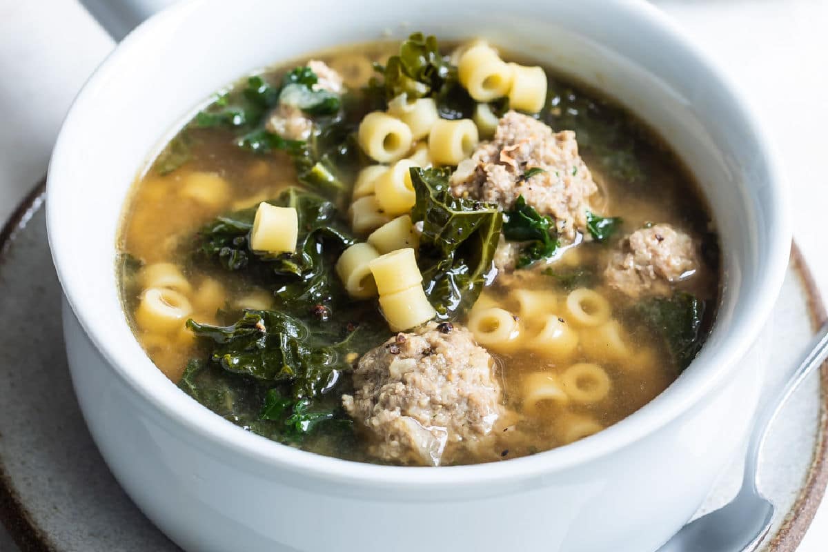 Italian wedding soup in a white bowl.