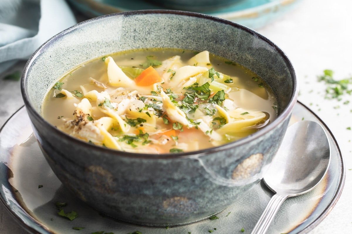 A gray bowl filled with leftover turkey noodle soup.