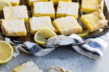 Lemon bars cut into squares on a baking sheet.
