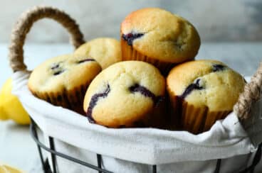 Lemon blueberry muffins in a basket with a bowl of blueberries.