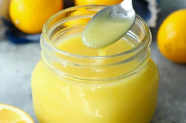 Lemon curd in a clear glass jar.