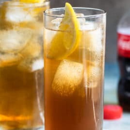 Two long island iced teas with a bottle of Coke in the background.