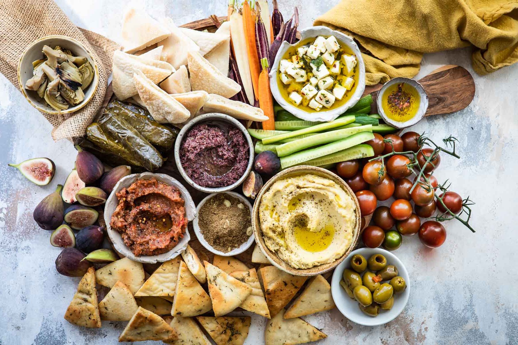 Dukkah, eggplant dip, hummus, artichokes, and olives in bowls