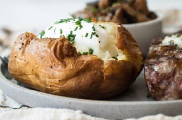 A baked potato topped with sour cream and chives.