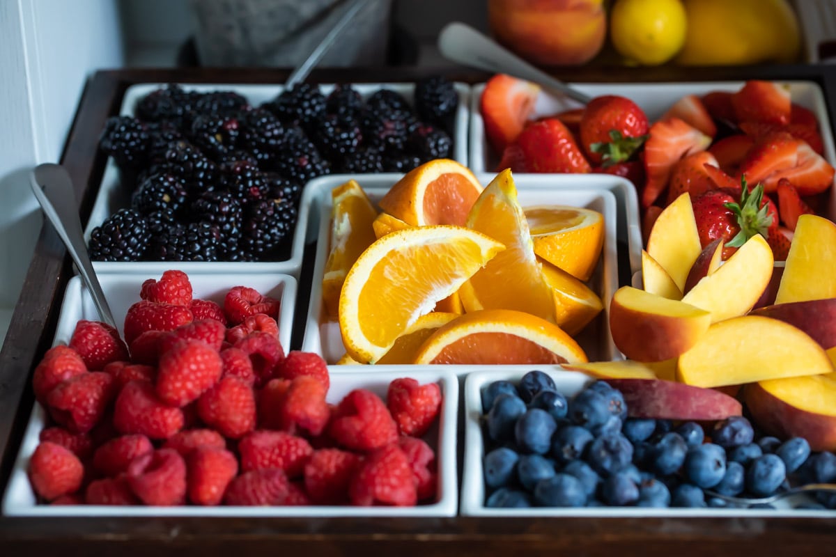 Carafes of juice, bottles of sparkling wine, and fresh fruit garnishes for a mimosa bar.