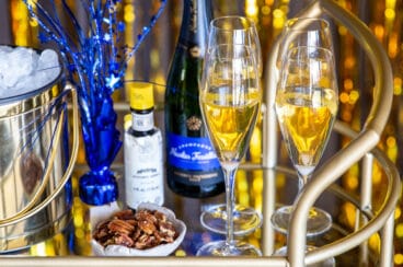 A bar cart with champagne cocktails, nuts and New Year's decorations.