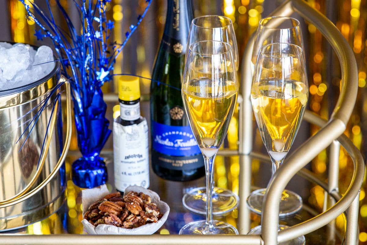 A bar cart with champagne cocktails, nuts and New Year's decorations.