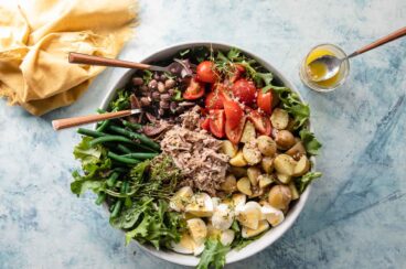 A Nįcoise Salad in a bowl with utensils.