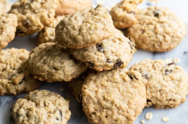 A pile of oatmeal raisin cookies on a marble plattter.