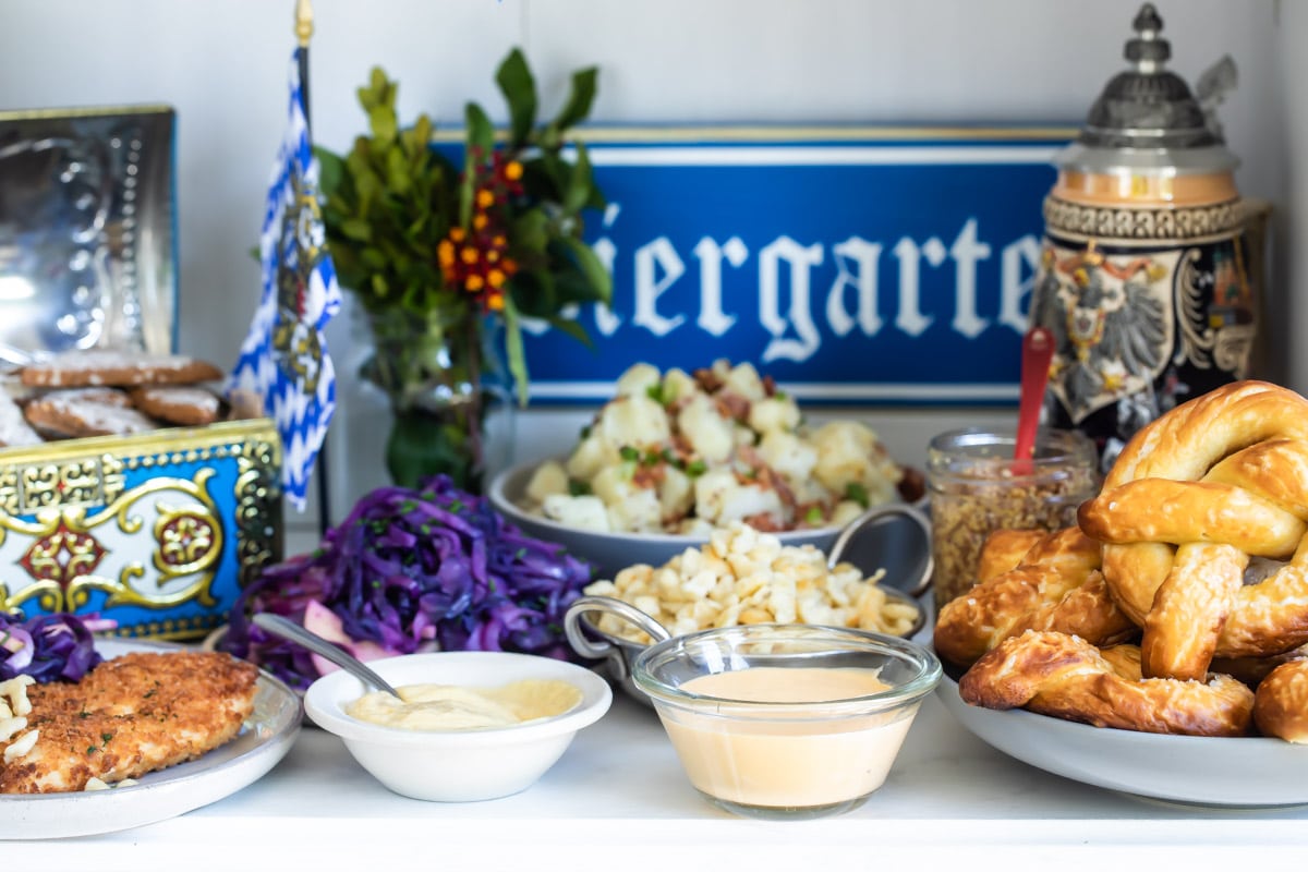 A table of Oktoberfest food including schnitzel, spaetzle, soft pretzels, German potato salad, Lebkuchen, and beer.