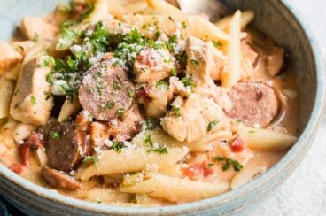 One pot cajun pasta in a blue bowl with a silver fork.