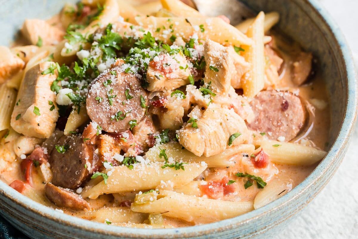 One pot cajun pasta in a blue bowl with a silver fork.