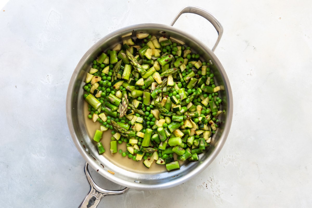Zucchini and asparagus cooking in a skillet.