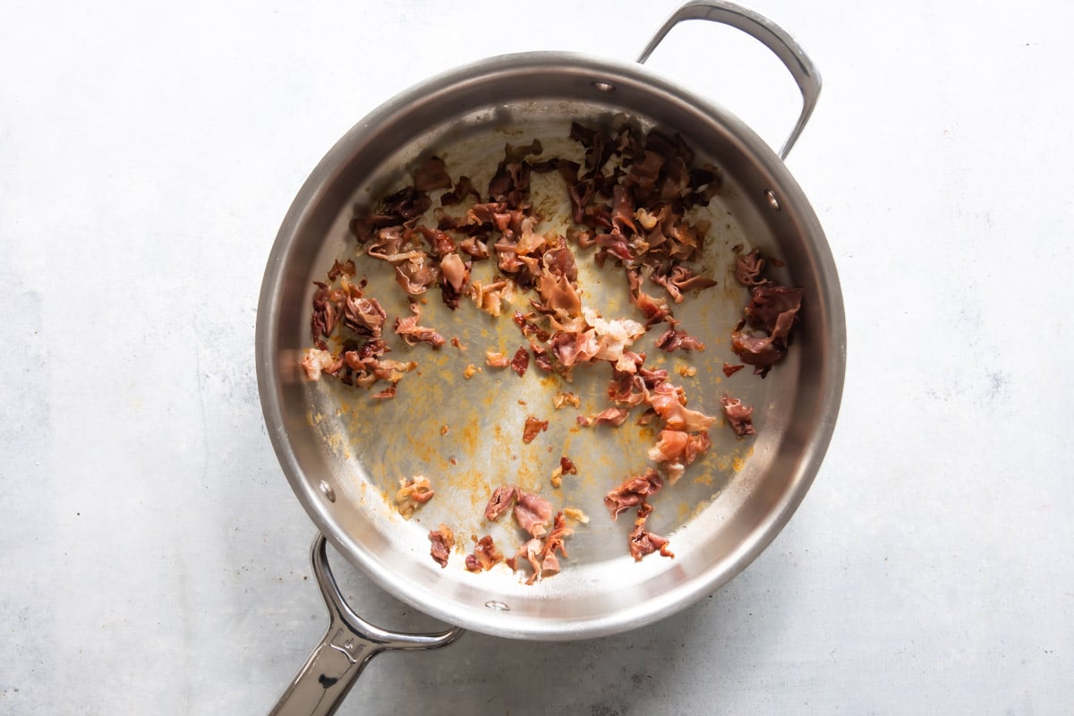 Prosciutto in a silver skillet.