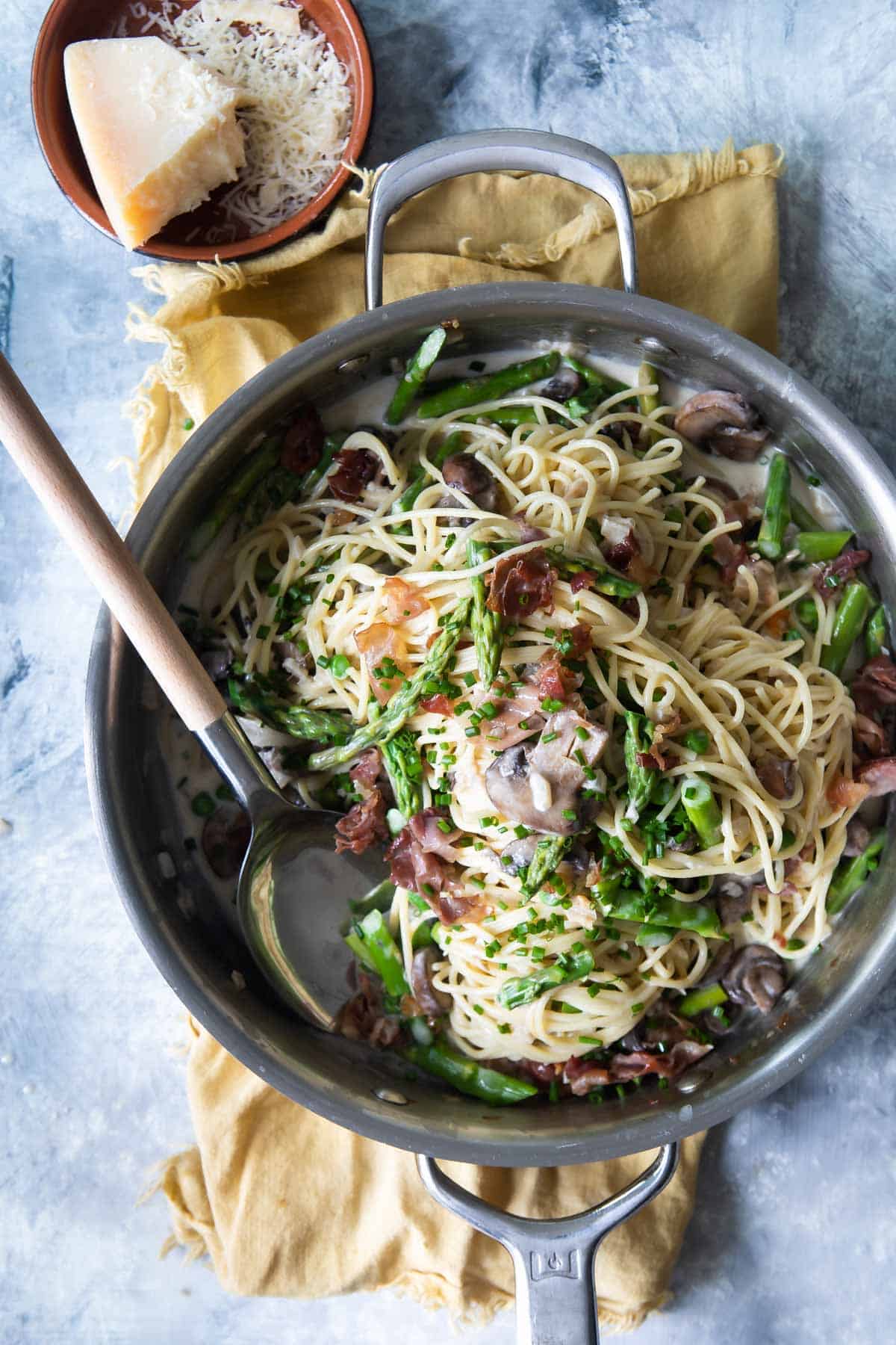 Pasta with peas and prosciutto in a silver skillet.