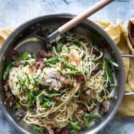 Pasta with peas and prosciutto in a silver skillet.
