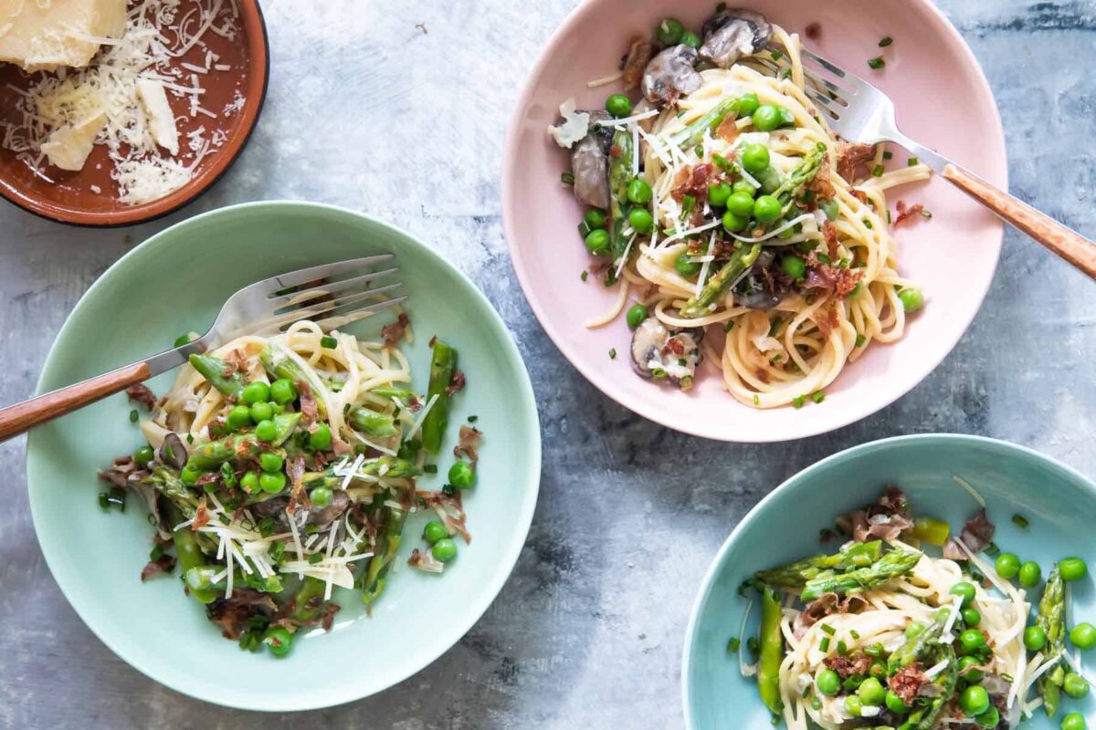Pasta with peas and prosciutto in pastel bowls.