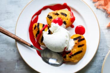 A plate of peach melba topped with raspberry coulis.