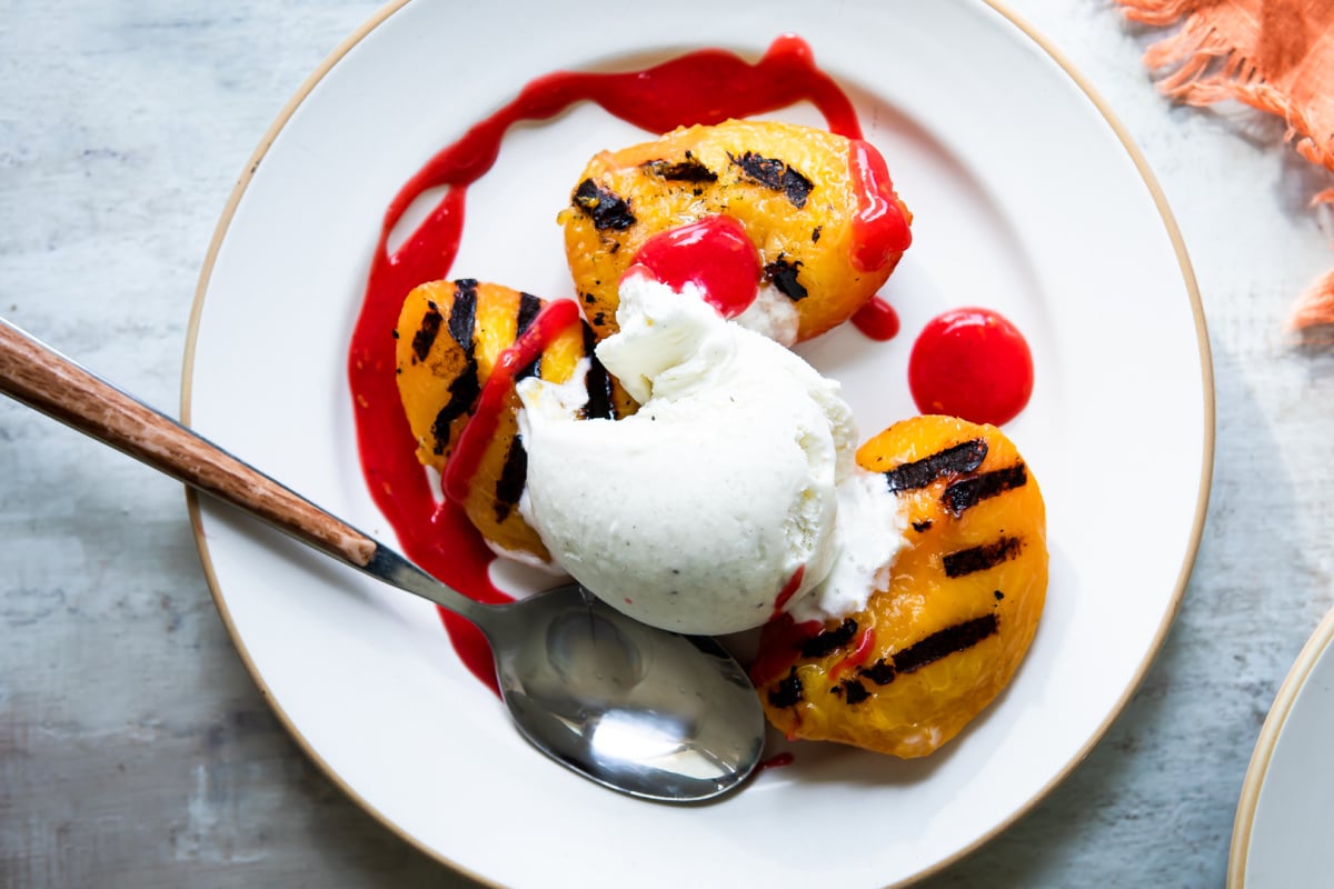 A plate of peach melba topped with raspberry coulis.