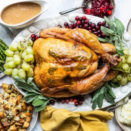 A roasted turkey on a platter with fruit.