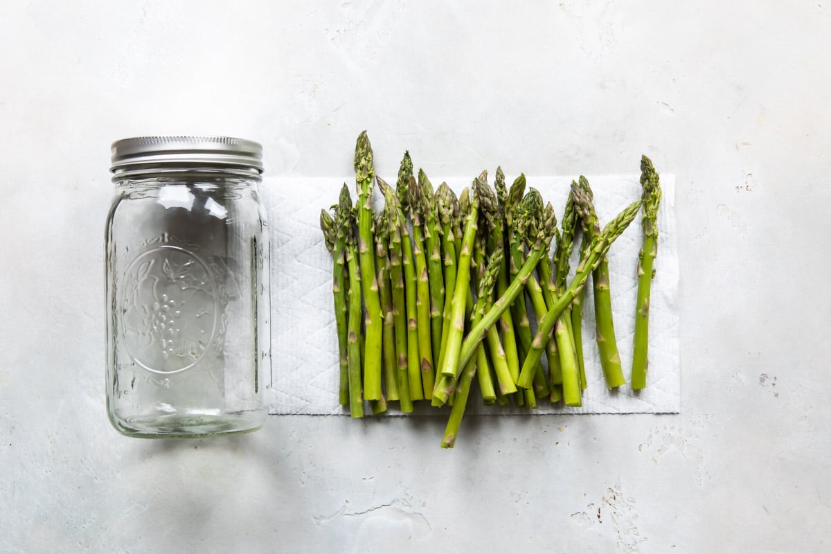 Asparagus stalks resting on a paper towel next to a mason jar.