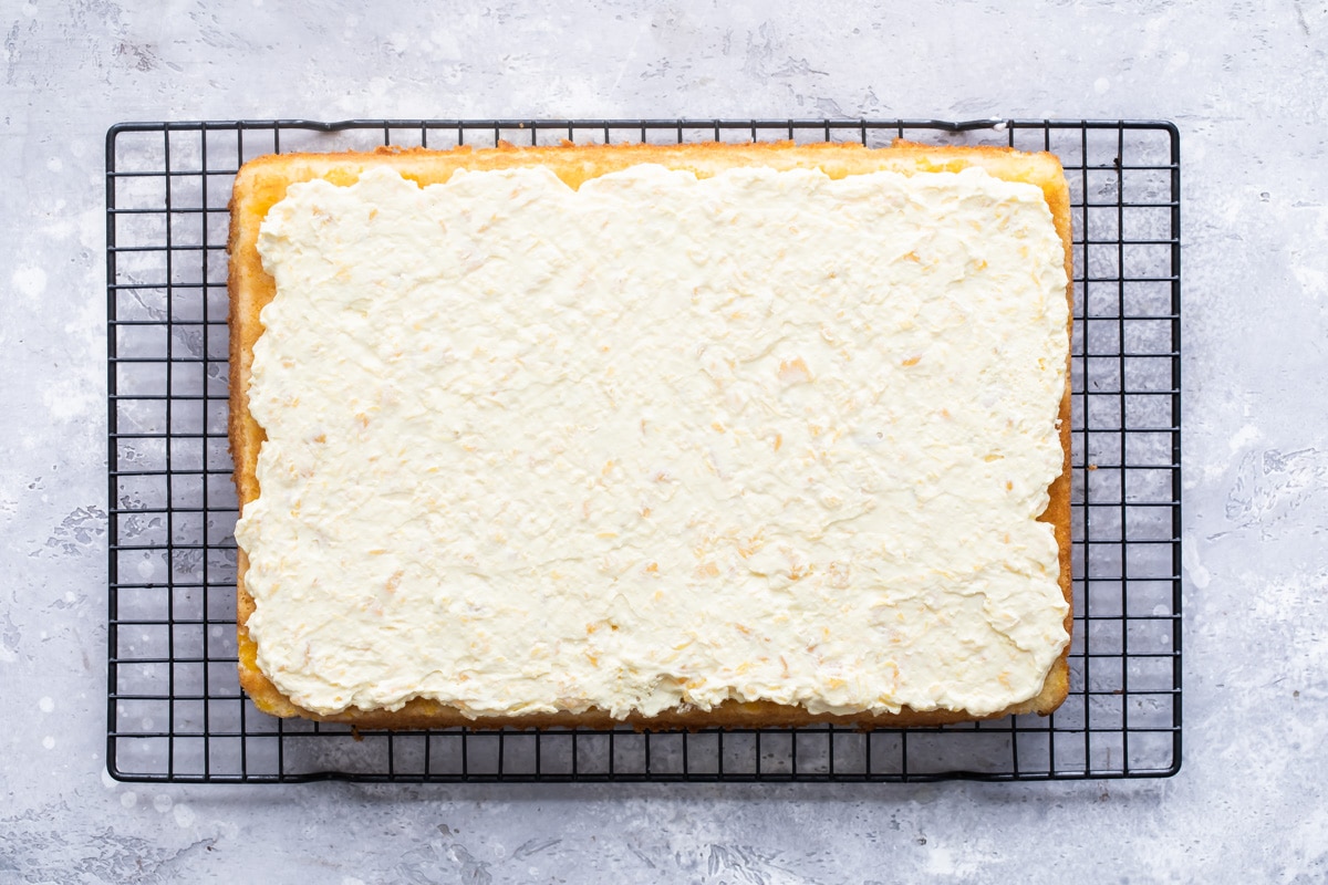 A frosted Pig Pickin' Cake on a black cooling rack.