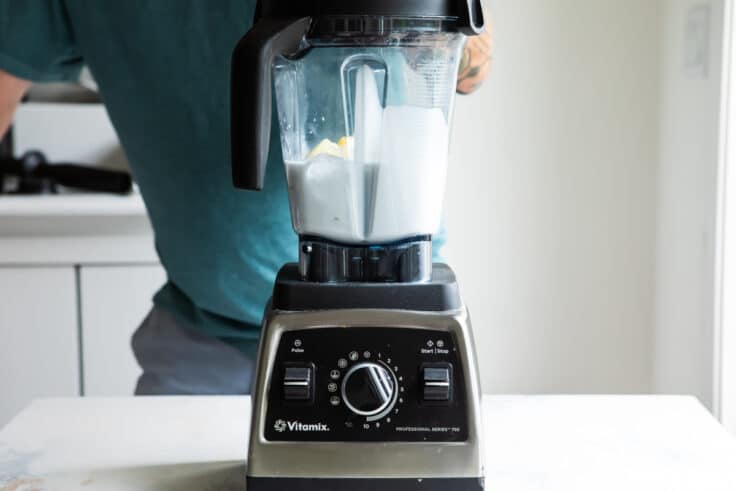 A blender with white liquid being mixed in it.