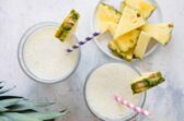 2 Pineapple Smoothies in glasses with striped straws.